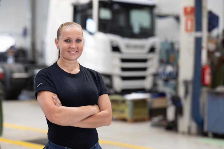 Kvindelig mekaniker, der står med armene over kors i et værksted